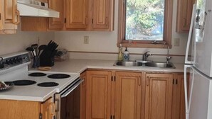 Una cocina con armarios de madera, estufa, fregadero y refrigerador.