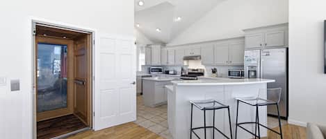 A modern kitchen with a central island, white cabinetry, and stainless steel appliances.