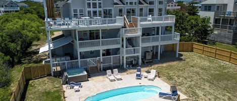 A two-story house with a swimming pool and outdoor furniture.