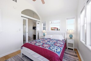 A bedroom with a bed, two bedside tables, a window, and a door leading to another room. - Sea Forevermore: Oceanside, Private Pool, 2 Hot Tubs, Elevator (Corolla)