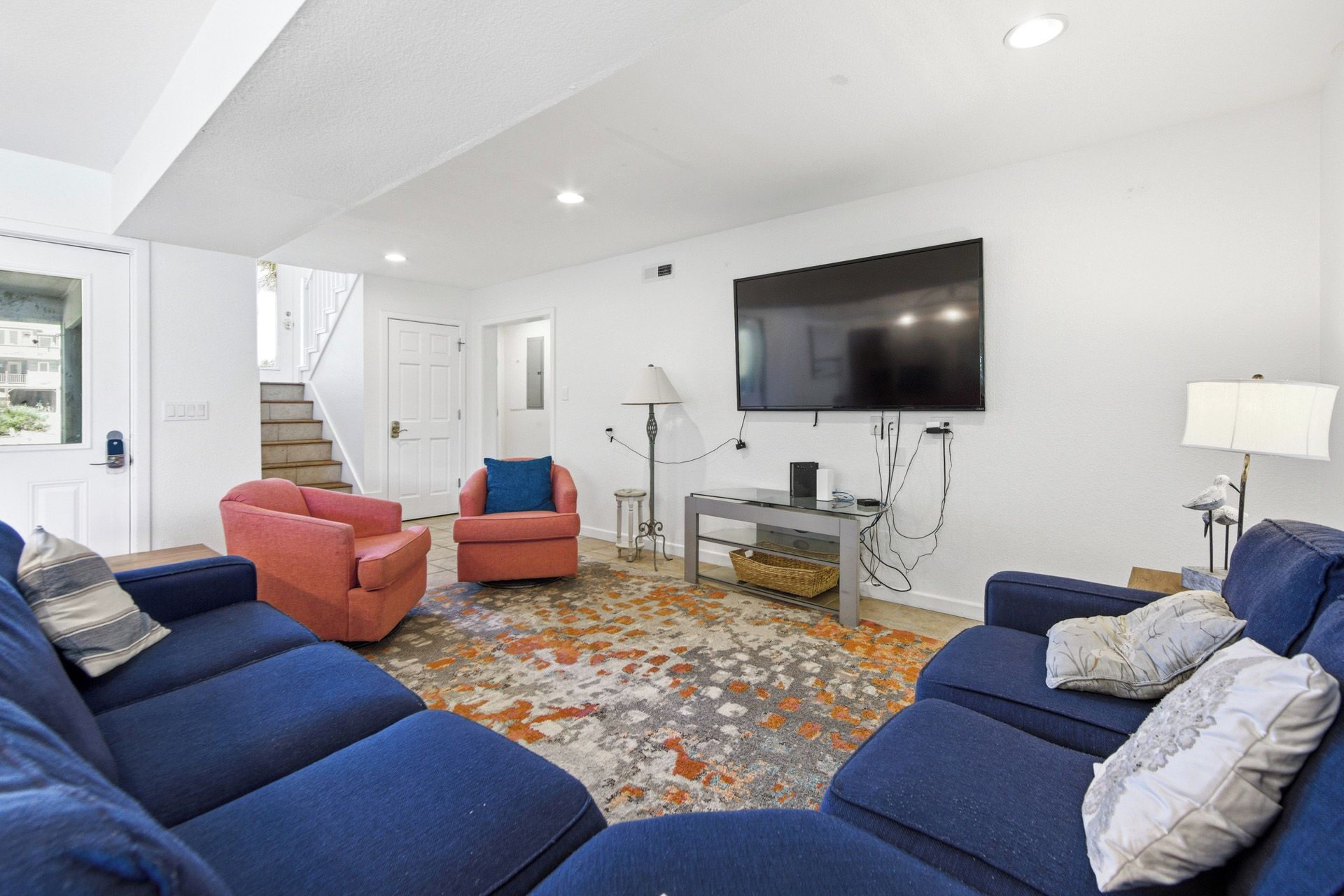 A modern living room with a flat-screen TV, two sofas, a coffee table, and a patterned rug.