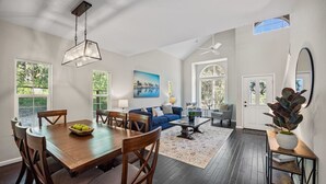 A spacious living area with a dining table, blue sofa, and a large window. - Serene, Stylish, and Spacious 3BD 2BA House Near Wineries (Sonoma)