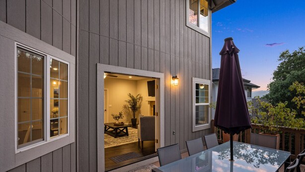 A patio with a glass table and chairs, a dark umbrella, and a view of the backyard. - Serene, Stylish, and Spacious 3BD 2BA House Near Wineries (Sonoma)