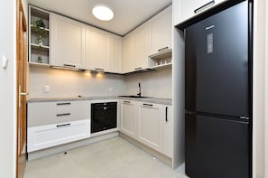Une cuisine moderne avec des meubles blancs, un réfrigérateur noir et un four encastré.