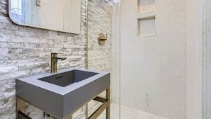 Une salle de bain moderne avec un mur en marbre, un grand lavabo et un miroir.