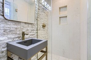 A modern bathroom with a marble wall, a large sink, and a mirror. - Secret oasis in the heart of Montrose, outdoor dining, firepit, gazebo and grill (Houston)