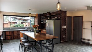 Una cocina moderna con una isla de madera, taburetes de bar y vistas al exterior.