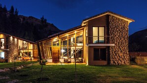 Una casa moderna con grandes ventanales, fachada de piedra y un espacio exterior bien iluminado.