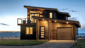 A modern two-story house with a garage, large windows, and a balcony. - Teton Homestead: Scenic Loft Retreat (Driggs)