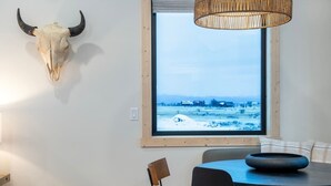 A dining area with a large window, a woven light fixture, and a mounted animal skull. - Teton Homestead: Scenic Loft Retreat (Driggs)