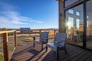 Una terraza con dos sillas y una mesa, con vistas a un área verde y montañas distantes.