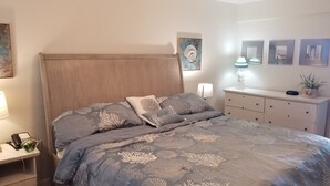 Une chambre à coucher comprenant un lit, des tables de chevet, une commode et des œuvres d’art murales.