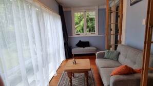 Un salon avec un canapé gris, une table basse en bois et une fenêtre ornée de rideaux blancs.