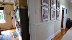 Un couloir avec un réfrigérateur, une horloge et des tableaux encadrés accrochés au mur.
