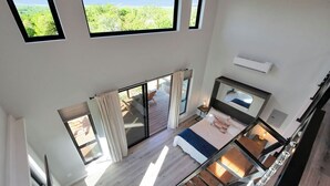 Una habitación con techos altos, una cama grande, un escritorio y vistas a un balcón.