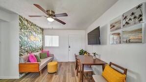 Ein Essbereich mit Holztisch und -stühlen, einem Deckenventilator und einem an der Wand befestigten Fernseher.