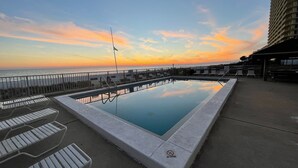 Ein Dachpool mit Blick auf den Sonnenuntergang über dem Meer, Liegestühle und eine Fahnenstange.