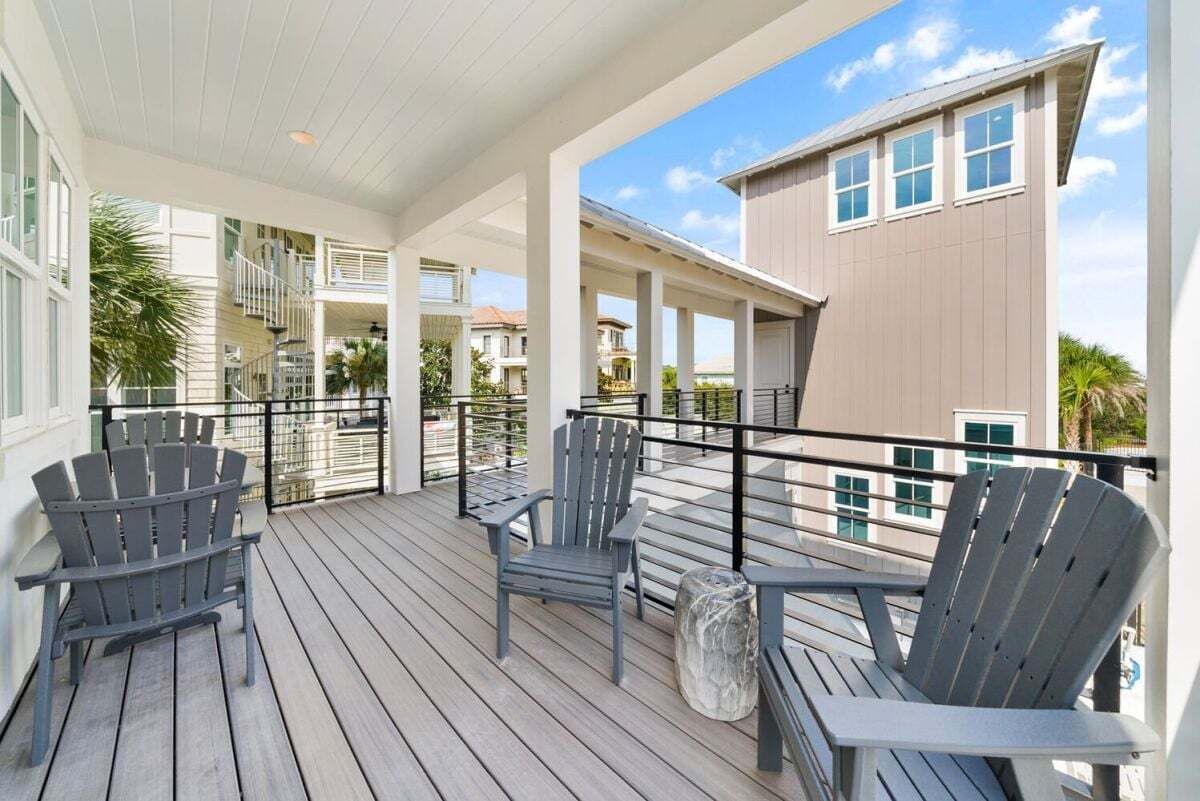 A covered outdoor deck with Adirondack chairs and a stone planter.