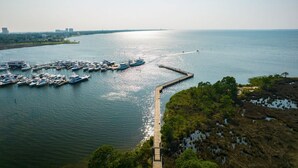 Ein Hafen mit mehreren vertäuten Booten, einer anlegenden Pier und einer entfernten Stadtansicht.
