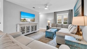 Ein Wohnzimmer mit großem Flachbildfernseher, Deckenventilator, Sofa, Couchtisch und Schrank.