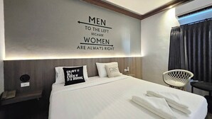 Una habitación de hotel moderna con una cama grande, un cabecero con una cita motivacional, una mesita de noche y una silla.
