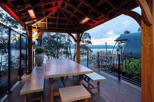 An outdoor wooden deck with a table and benches, overlooking a body of water and trees. - Sanctuary Bruny Island - 2 Domes (Adventure Bay)