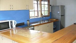 Una cocina con encimera de madera, microondas, fregadero y refrigerador.