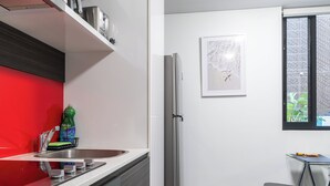 Ett modernt kök med en röd väggbeklädnad bakom arbetsbänken, rostfria vitvaror, ett kylskåp och ett fönster med utsikt.