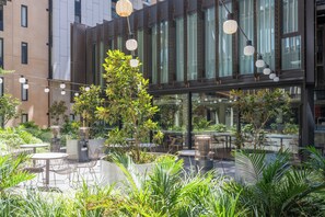 An outdoor patio area with seating, potted plants, and string lights. - Zen Apartments (Adelaide)