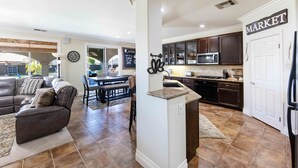 A spacious living room with a dark leather sofa and a dining area with a table and chairs. A kitchen with dark cabinets and a microwave is visible. - Wine Country Resort  -  Close to Wineries (Winchester)