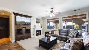 A living room with a fireplace, leather sofa, and a television mounted on the wall. - Wine Country Resort  -  Close to Wineries (Winchester)