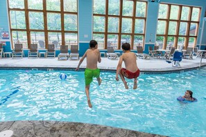 An indoor swimming pool with clear blue water, wooden deck chairs, and large windows. - Near Thunder Ridge & Table Rock: Private Hot Tub, Community Pool & Free Tickets (Hollister)
