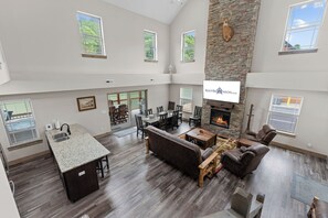 A spacious living area with a fireplace, a dining table, and a kitchen with a granite countertop. - Near Thunder Ridge & Table Rock: Private Hot Tub, Community Pool & Free Tickets (Hollister)