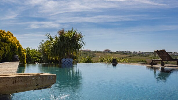 Una piscina con vistas despejadas del paisaje circundante, incluyendo árboles y edificios distantes.