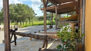 Un patio al aire libre con una pérgola de madera, asientos y un muro de piedra.