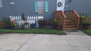 Un edificio con valla de piquete blanca, plantas en macetas y una escalera de madera que conduce a una puerta.