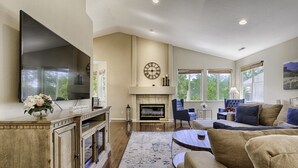 Un salón amplio con chimenea, un televisor de pantalla plana grande y asientos cómodos.