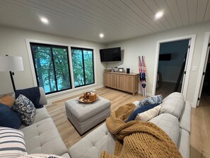 Un salon moderne doté d’une grande fenêtre, d’un téléviseur à écran plat, d’un meuble en bois et d’un porte-skis.