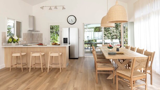 Una cocina moderna con una isla central, sillas de madera y una mesa de comedor con sillas de mimbre.