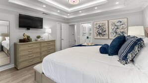 A bedroom with a large bed, a dresser, a flat-screen TV, and artwork on the walls. - Luxurious Townhome/Beach Access/11 Pools (Panama City)