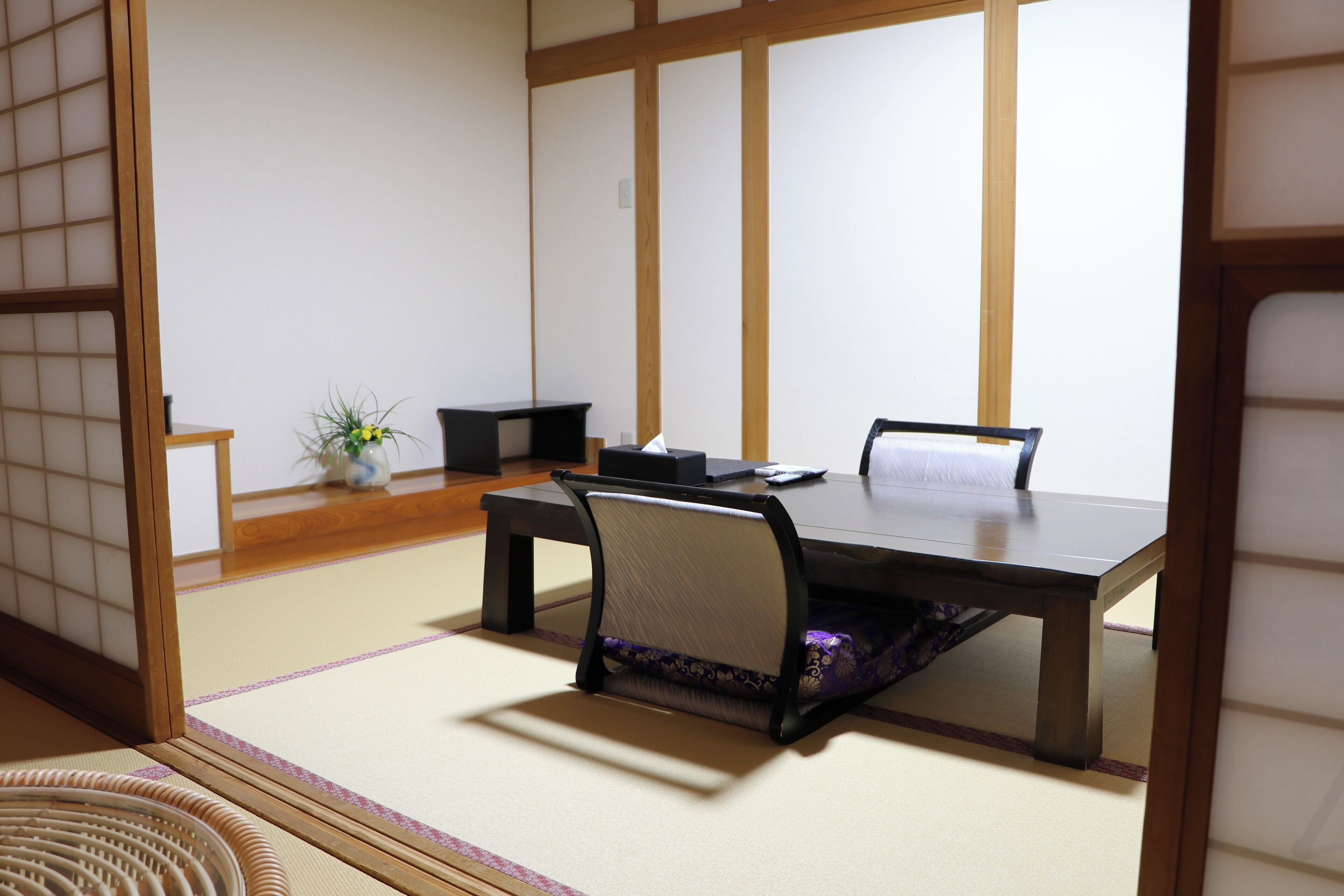 Una habitación japonesa tradicional con suelo de tatami, una mesa baja y una silla.