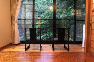 Una habitación con un ventanal grande, dos sillas, suelo de madera y una puerta.