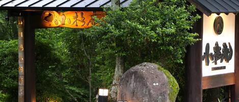 A traditional Japanese torii gate with a large rock in front, surrounded by lush greenery.