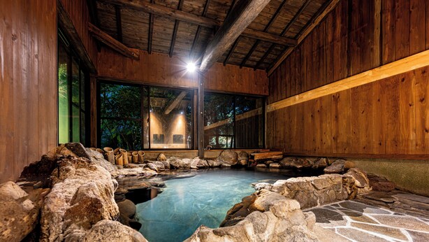 Un bain traditionnel en bois, avec une source d’eau chaude entourée de pierres.