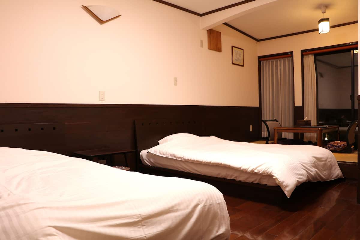 Een hotelkamer met twee bedden, een houten hoofdbord, een tafeltje en een spiegel.