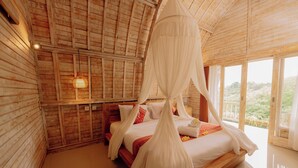 Une pièce en bois avec un lit, un luminaire suspendu et une vue dégagée grâce à de grandes fenêtres.