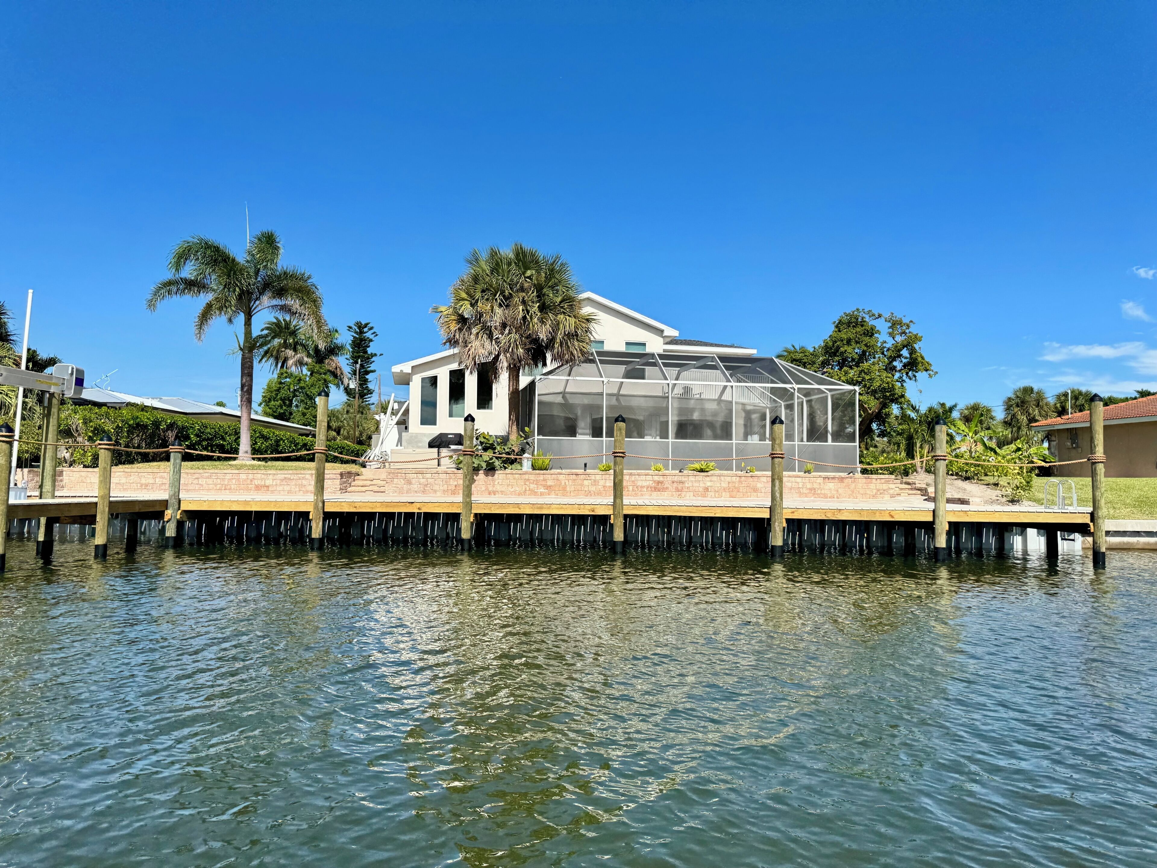 A house with a glass greenhouse attached to the main building, situated on a dock over water.