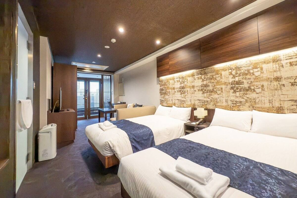 Een hotelkamer met twee bedden, een bureau en uitzicht op buiten.