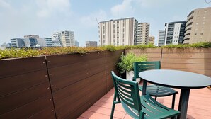 Una terrazza sul tetto con un muro in legno, un tavolo e due sedie.