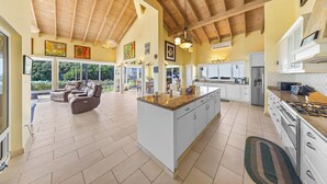 A spacious kitchen with a large island, white cabinetry, and a wooden ceiling.
